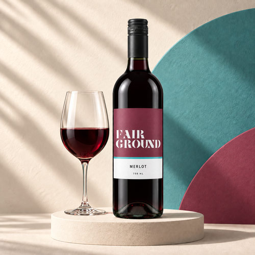 Fairground Merlot bottle and a glass of red wine on a cream plinth with a teal and label-coloured backdrop